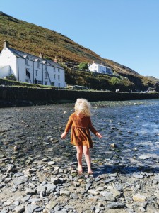 girl dipping toes in water, white cottages, blue skies, boscastle, cornwall